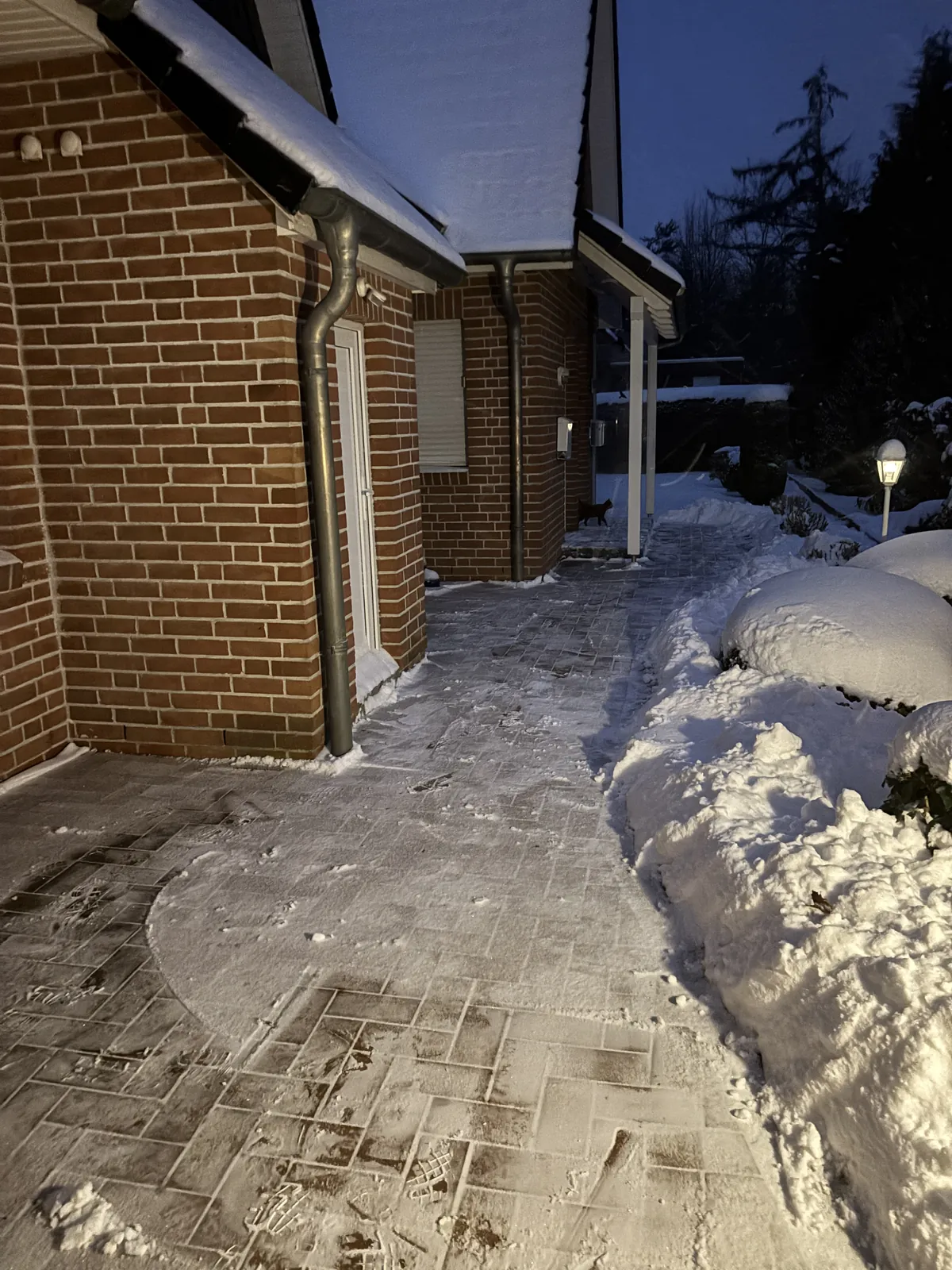 Geräumter Weg neben einem Haus nach dem Schneeräumen