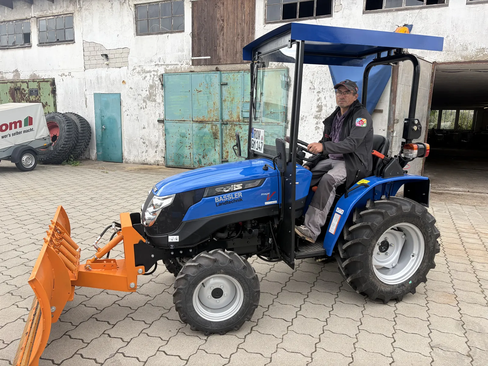 Kleintraktor mit Schneeschild auf einem Hof
